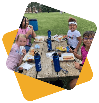 Four girls sitting at a picnic bench and eating lunch